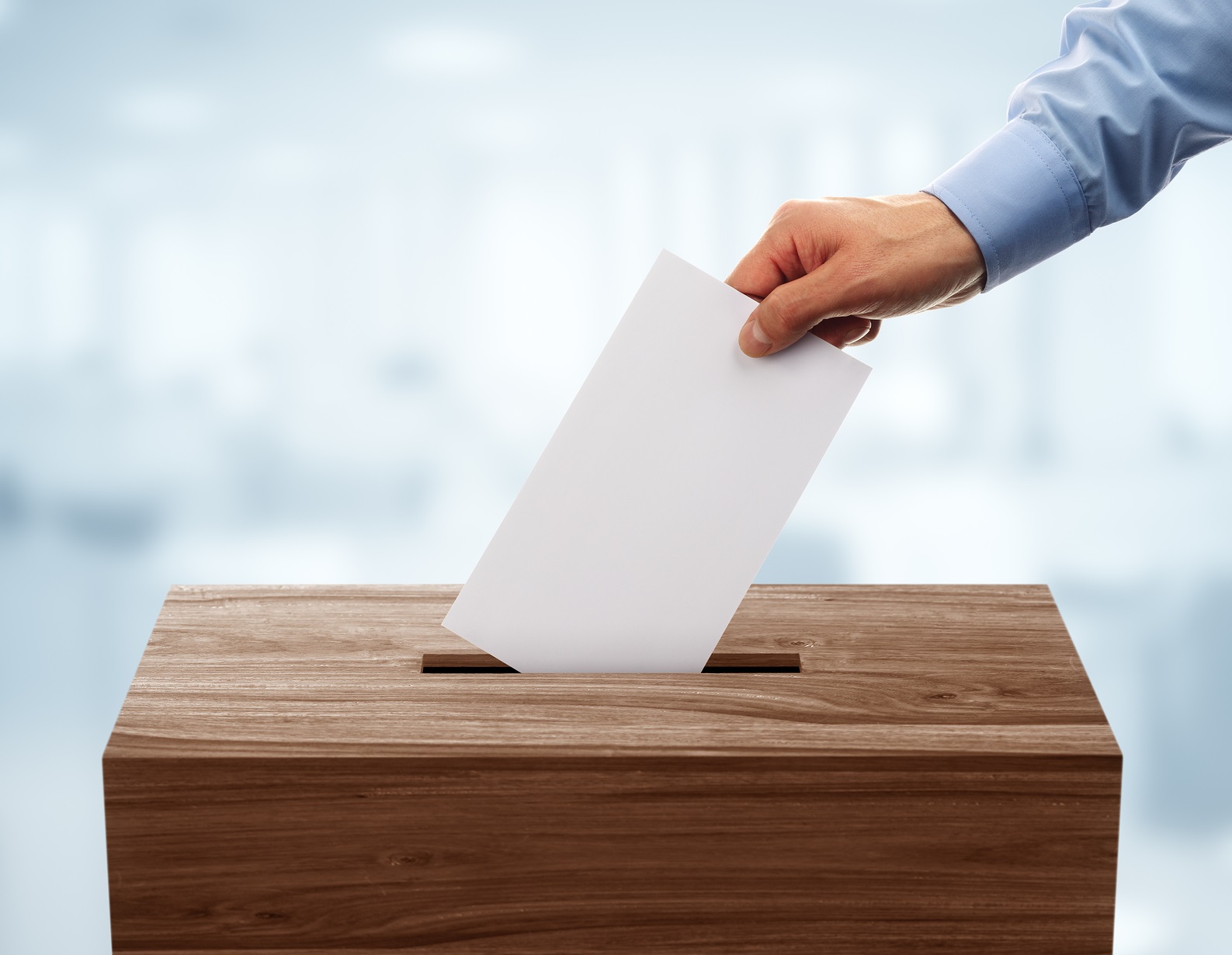 Ballot box with person casting vote on blank voting slip