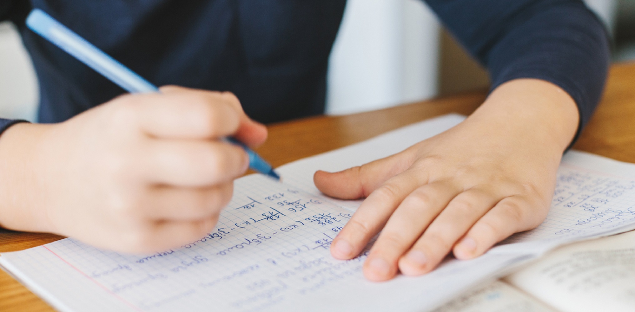 Schoolboy doing his homework on desk at home.