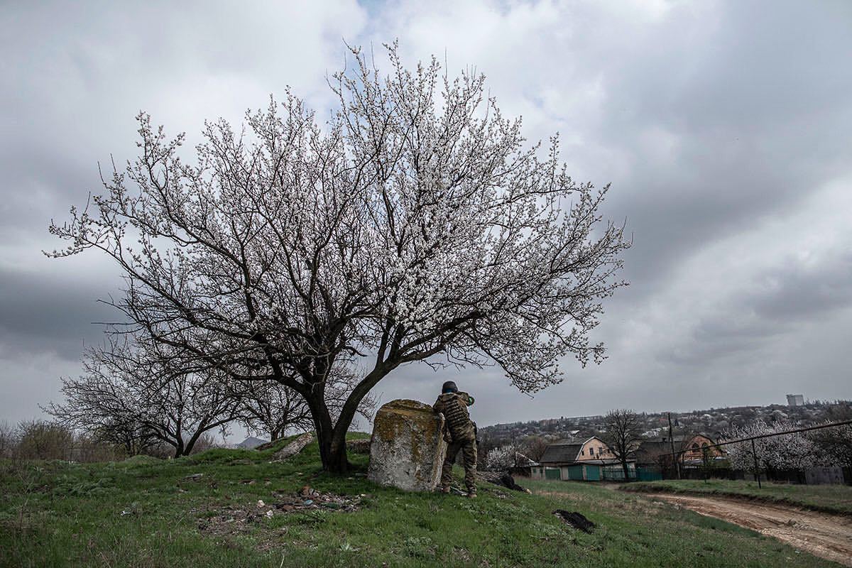 країнський військовослужбовець здалеку оглядає в бінокль дорогу на Мар’їнку. Квітень, 2022