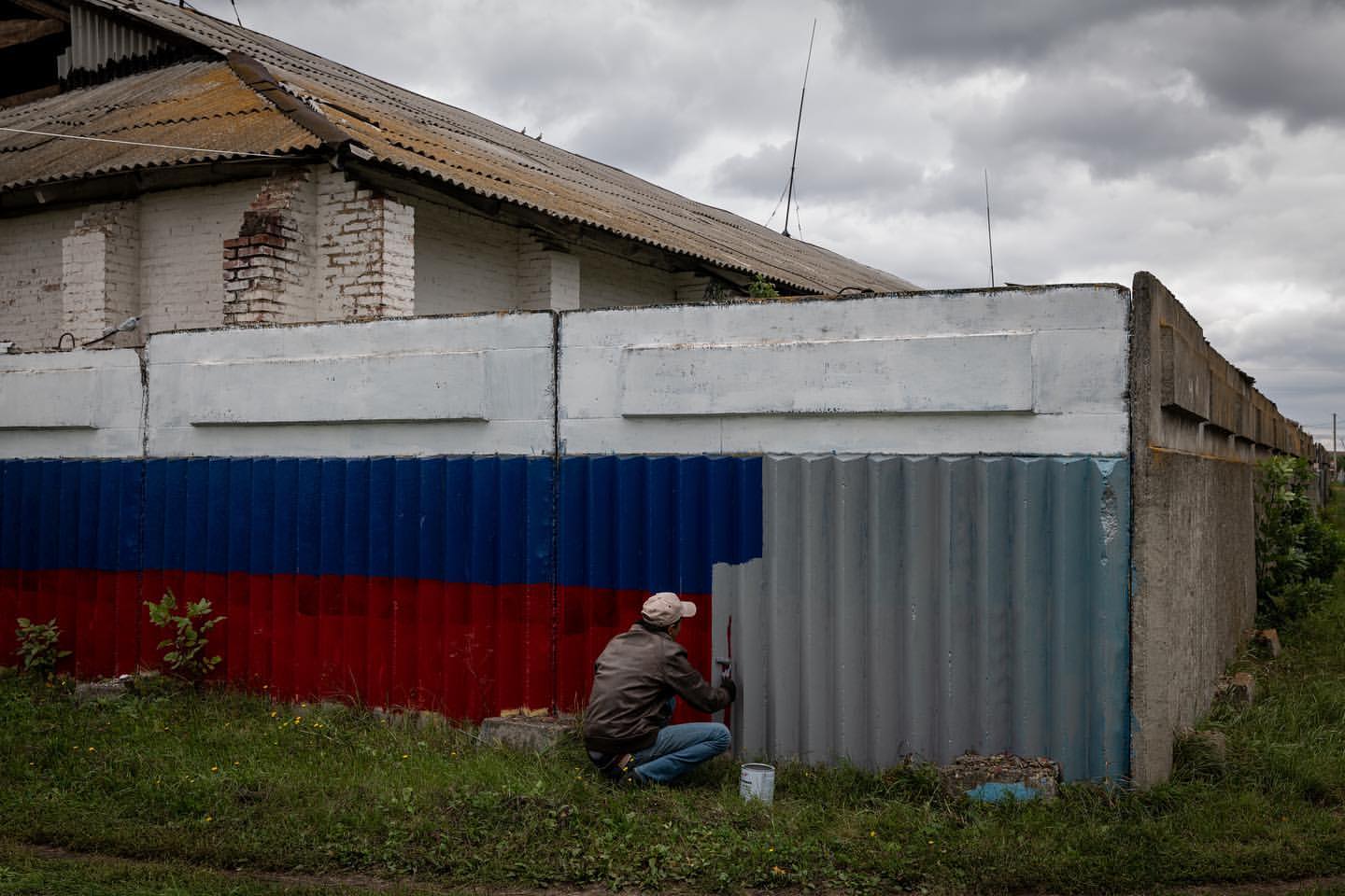 Ілюстративне фото. Чоловік зафарбовує російський прапор у нещодавно звільненому селі.