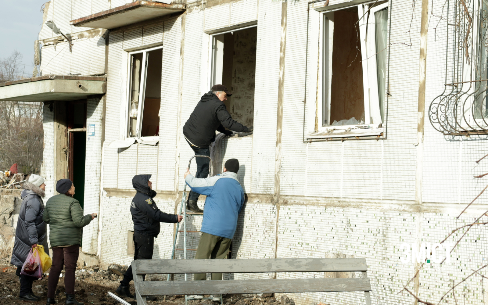 Чоловік намагається дістатися до квартири в обстріляному будинку
